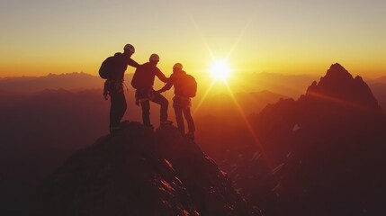 Fototapeta premium Teamwork: Three climbers help each other on a mountain top at sunrise. 