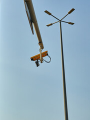 CCTV camera on a street light pole with blue sky background.