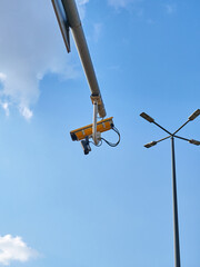 CCTV camera on a street light pole with blue sky background.