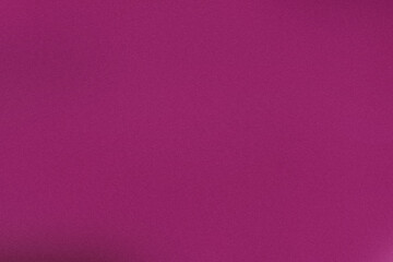 The fabric exhibits a rich magenta hue, folding softly across the table, capturing light beautifully and emphasizing its smooth texture in this indoor environment