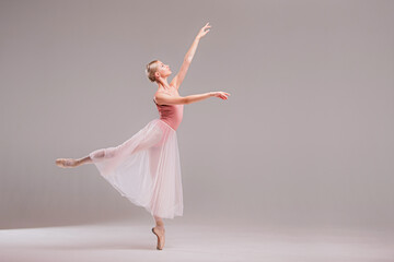 Ballerina in pink leotard dancing on white background.