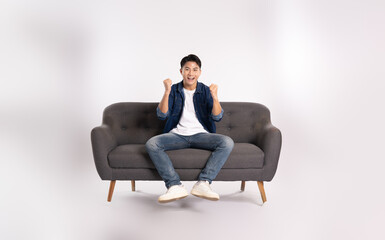 Full body image of young Asian man posing on sofa on white background
