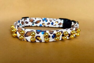 On a brown background lies a black leopard collar for cats and dogs with a plastic fastex clasp