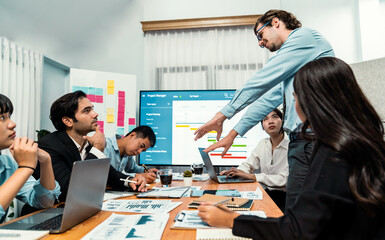 Project manager planning schedules for business task at meeting room, Gantt chart software show on TV screen. Multi ethnic diversity business people and modern business project management. Habiliment