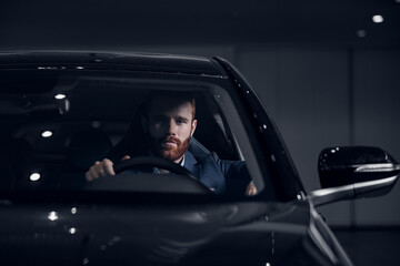 Portrait handsome bearded man driving luxury car. Concept professional driver business taxi