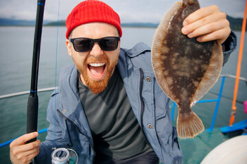 Happy Scandinavian fisherman caught flounder fish with fishing rod, trip Kamchatka Russia....