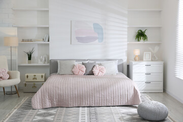 Large bed, houseplants and decorative elements in room. Stylish bedroom interior