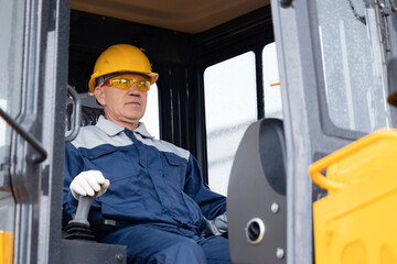 Portrait happy adult man builder in hardhat driver of excavator working at construction site
