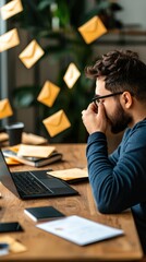 Fototapeta premium A man stressed by incoming emails, sitting at a desk with a laptop, surrounded by floating envelopes, representing digital communication chaos.