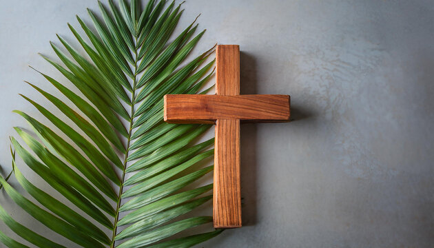 Wooden Cross and green palm leaf on cement background. Religion and Christian fait concept.