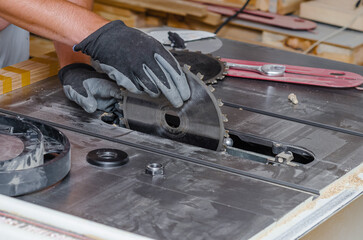 carpenter replaces circular saw in machine tool. Replacing saw in carpentry shop