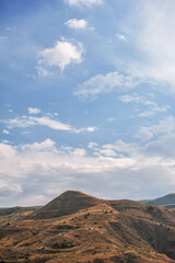 Majestic mountains under a blue sky filled with clouds, showcasing natural beauty and rugged terrain