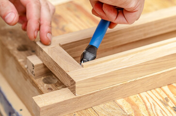 carpenter applies glue with brush to wooden boards in workshop