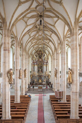 Obraz premium The interior features stunning late Gothic architecture, showcasing intricate vaulted ceilings, wooden pews, and golden statues adorning the walls, creating a serene atmosphere for worship.