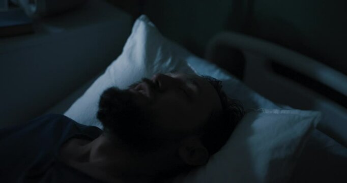 In a hospital room, a troubled-looking guy with disheveled hair screams out loud.