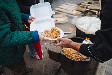 A person is giving a plate of food to another person