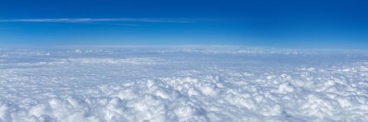 Fluffy white clouds blanket the sky under a clear blue horizon, evoking tranquility and freedom, ideal for travel inspiration