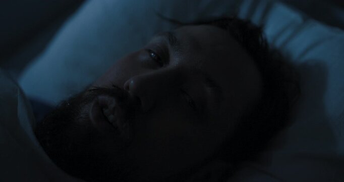 Young man in a hospital bed stares intensely into the camera,