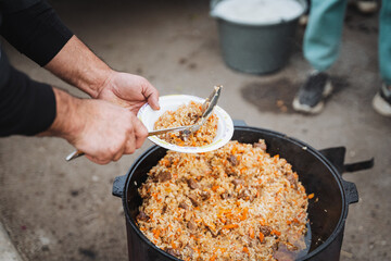 An individual is carefully placing a diverse selection of delicious ingredients from a hot pot onto a clean plate, thoughtfully arranging them for an appealing meal presentation