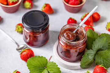 Two jars of delicious homemade strawberry jam surrounded by fresh strawberries
