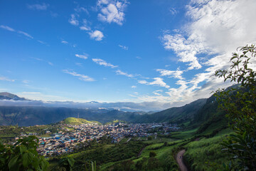 Naklejka premium Fotografía panorámica de un pueblo entre montañas verdes en un cielo azul 