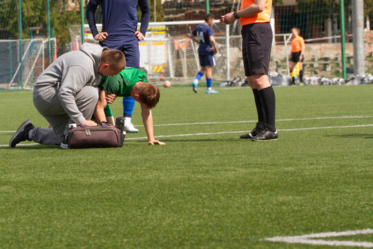 A sports doctor provides first aid to an athlete on the football field.