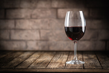 A dark, elegant still life of red wine in a glass with wooden background. Perfect for wine-themed compositions