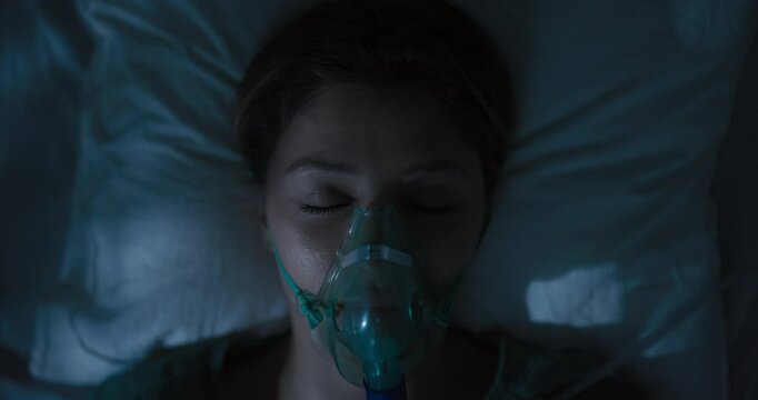 Female patient wearing oxygen mask looking directly at camera.