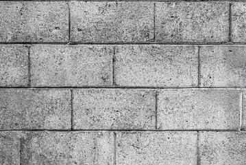 Black and white image of rough concrete block wall texture with visible wear and marks.