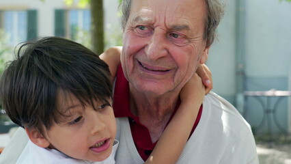 Fototapeta premium Young boy affectionately hugs his elderly grandfather outdoors, sharing a moment of closeness and love, tender expression. intergenerational connection and family bonds