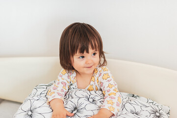 Fototapeta premium Pillow fight time, a little baby-girl loves playing with her pillow