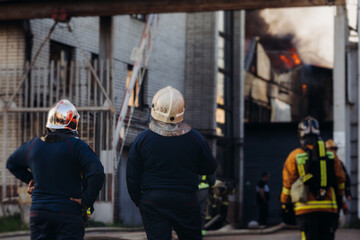 Group of fire men in uniform during fire fighting operation in the city streets, firefighters with the fire engine truck vehicle in the background, emergency and rescue, fire drill, exercise training