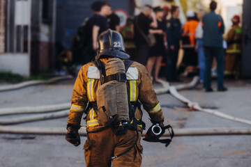 Fototapeta premium Group of fire men in uniform during fire fighting operation in the city streets, firefighters with the fire engine truck vehicle in the background, emergency and rescue, fire drill, exercise training