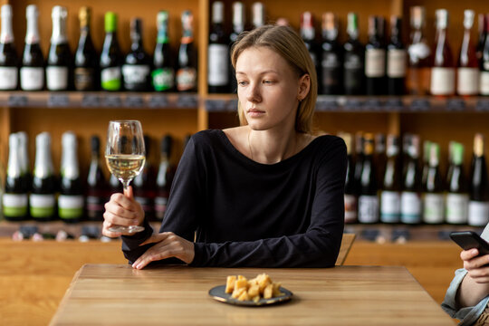 White woman drinks white wine in wineshop