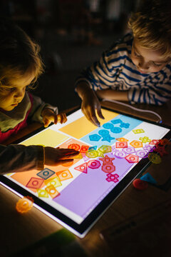 Two kids paying with a lightpad in the dark