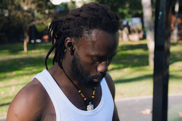 Close up of black ethnic man looking down in the park