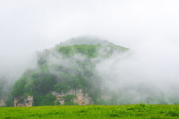 Dramatic view of the harsh green mountain in the clouds in bad weather. The North Caucasus. Russia
