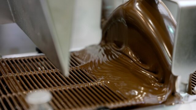 Chocolate tempering machine pouring melted chocolate.
