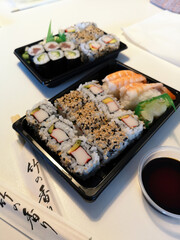 A delicious sushi bento box features fresh rolls, nigiri, and dipping soy sauce, beautifully arranged for a delightful dining experience.