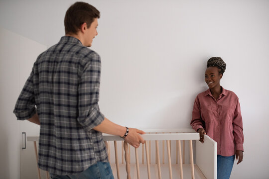 Loving couple assembling baby bed