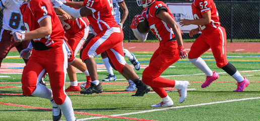 Fototapeta premium Football running back running toward the line of scrimage behind his blockers