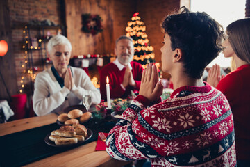 Photo of four peaceful family members sit table praying celebrate christmas eve dinner apartment...