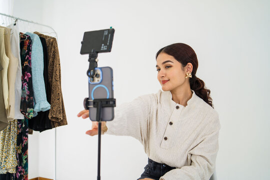 Young latina woman smiling in front of her cell phone recording