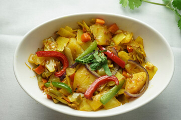 Bowl of mixed vegetables showcases a colorful array of red and green peppers, carrots, and yellow cabbage, all stir-fried to perfection. The dish is garnished with fresh herbs, adding a pop of green.