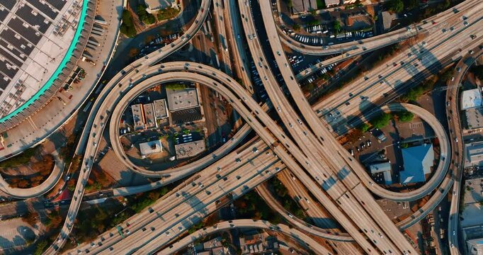 Los Angeles interchange with numerous cars moving by. Busy traffic on the highways of metropolis downtown. Top view.