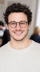 Fototapeta premium A cheerful young male employee with glasses enjoying a moment at his office workstation while his team collaborates in the background