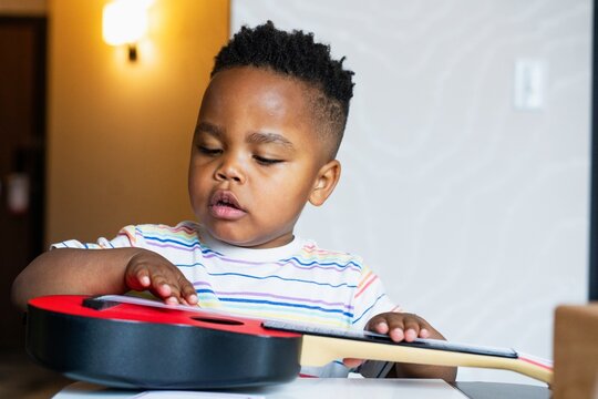 Child Playing with Toy Guitar
