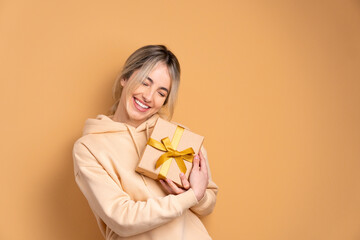 happy brazilian woman with gift box present in beige background. christmas, happy birthday, celebration concept.