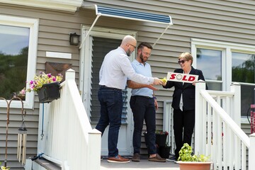 Realtor Handing Over "SOLD" Sign to Homebuyers