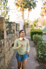 Fototapeta premium A young woman jogs energetically in a vibrant urban setting, enjoying her morning leisure